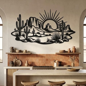 A black metal desert landscape wall sculpture is displayed on a tiled kitchen wall above a counter.