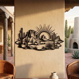 A black metal saguaro cactus landscape wall art piece is mounted on an exterior stucco wall of a patio.