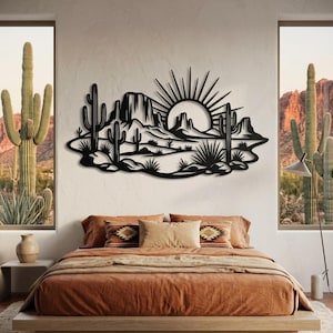 A black metal desert sunset sign is centered on a bedroom wall above a platform bed with orange bedding.