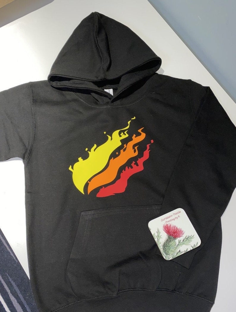 May include: Black hoodie with a yellow, orange, and red flame graphic on the front. The hoodie has a pocket on the front and a drawstring hood.