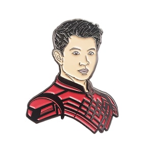 Puede incluir: Un pin de esmalte que representa un retrato de dibujos animados de un hombre con cabello negro que lleva un traje rojo y negro.