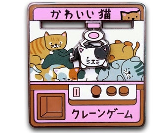 May include: A pink and brown claw machine with the Japanese text "kawaii neko" (cute cat) and "crane game". The machine is filled with plush cat toys, including a black and white cat with a halo.