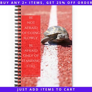 May include: A spiral-bound notebook with a red and white background featuring a tortoise. The notebook has a red rectangle with the text "BE NOT AFRAID OF GOING SLOWLY, BE AFRAID ONLY OF STANDING STILL" and "CHINESE PROVERB".
