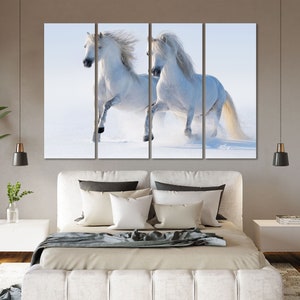 May include: Two white horses running through a snowy field. The horses are running side by side, with their manes flowing in the wind. The snow is falling softly around them, creating a beautiful winter scene.