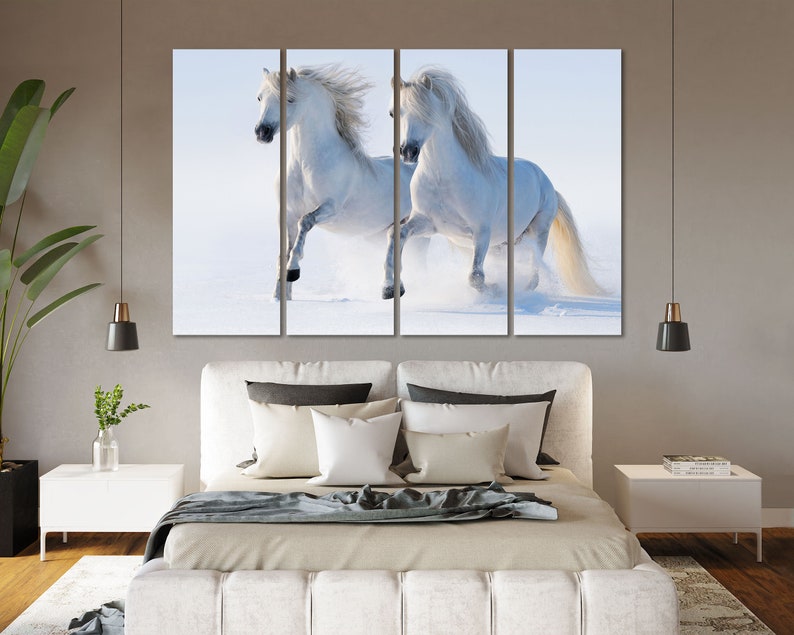 May include: Two white horses running through a snowy field. The horses are running side by side, with their manes flowing in the wind. The snow is falling softly around them, creating a beautiful winter scene.
