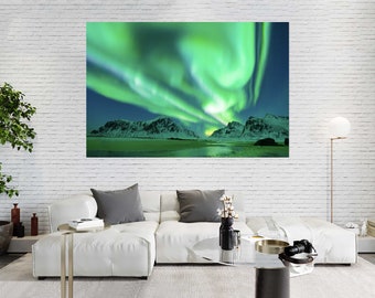 May include: A large rectangular canvas print shows the aurora borealis over a snowy mountain range. The sky is a deep blue, with vibrant green and white light displays. The print is displayed above a white sectional sofa.