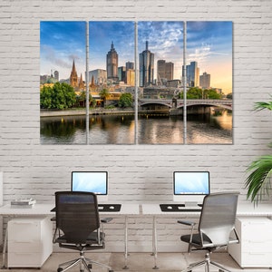 May include: A panoramic view of the Melbourne skyline with a bridge in the foreground. The city is bathed in the warm glow of sunrise, with the buildings reflecting the light. The river is calm and still, with a few boats visible in the distance.
