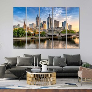 May include: A panoramic view of the Melbourne skyline with modern skyscrapers and a bridge over a river. The city is bathed in warm sunlight, creating a vibrant and inviting atmosphere.