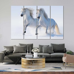 May include: Two white horses run through a snowy field. The horses are running side by side, with their manes flowing in the wind. The snow is falling softly around them, creating a beautiful winter scene.