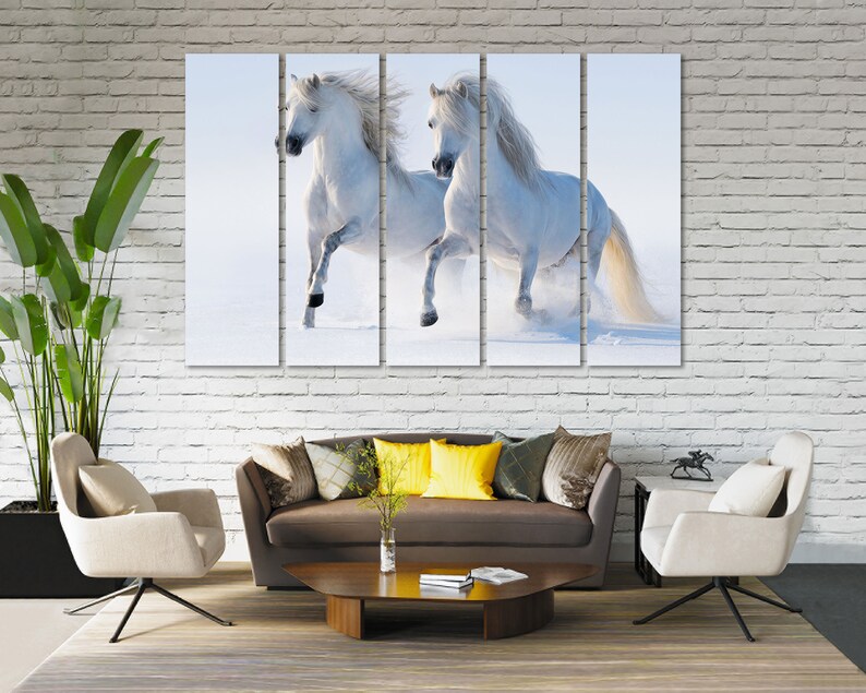 May include: Two white horses running through a snowy field. The horses are running side by side, with their manes flowing in the wind. The snow is flying up around them as they run.
