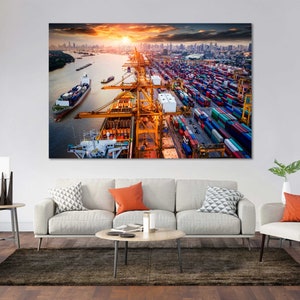 May include: An aerial view of a bustling shipping port with cargo containers stacked high and cranes loading and unloading ships. The sun is setting in the background, casting a warm glow over the scene.