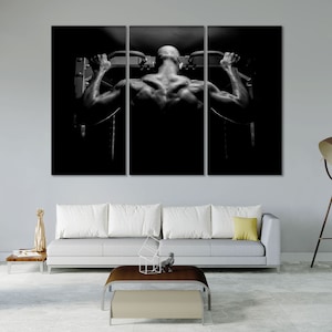 May include: Black and white photo of a person doing a pull-up exercise on a gym machine.