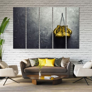May include: A set of three canvas prints featuring a pair of gold boxing gloves hanging on a textured gray background.