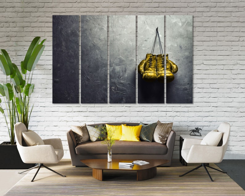 May include: A set of three canvas prints featuring a pair of gold boxing gloves hanging on a textured gray background.
