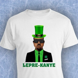K&ouml;nnte beinhalten: Wei&szlig;es T-Shirt mit einer Cartoon-Abbildung eines Mannes in einem gr&uuml;nen Leprechaun-Hut, Sonnenbrille und Anzug. Der Text "LEPRE-KANYE" ist unter dem Bild gedruckt.