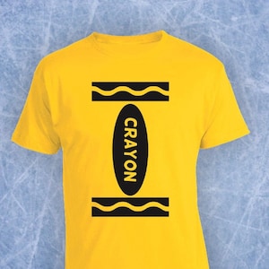 May include: Yellow t-shirt with a black crayon graphic. The crayon is labelled "CRAYON".