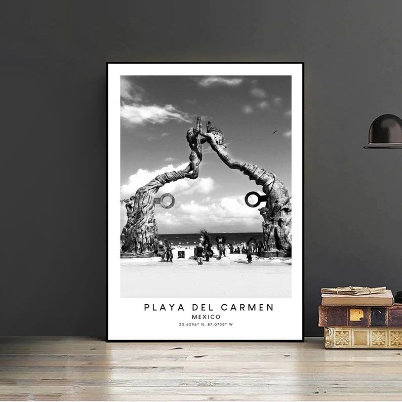 Pode incluir: Fotografia a preto e branco de uma grande escultura de madeira numa praia em Playa del Carmen, M&eacute;xico. A escultura &eacute; feita de duas figuras que se estendem as m&atilde;os uma para a outra. A escultura est&aacute; localizada numa praia de areia com pessoas a caminhar em fundo. O texto "PLAYA DEL CARMEN M&Eacute;XICO 20.6296&deg; N, 87.0735&deg; W" est&aacute; impresso abaixo da imagem.