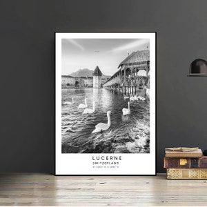 Peut inclure: Impression encadr&eacute;e en noir et blanc de Lucerne, Suisse. L'image pr&eacute;sente des cygnes nageant dans un lac, un pont en bois et une tour. Le texte "LUCERNE SWITZERLAND" est imprim&eacute; en bas, avec les coordonn&eacute;es.