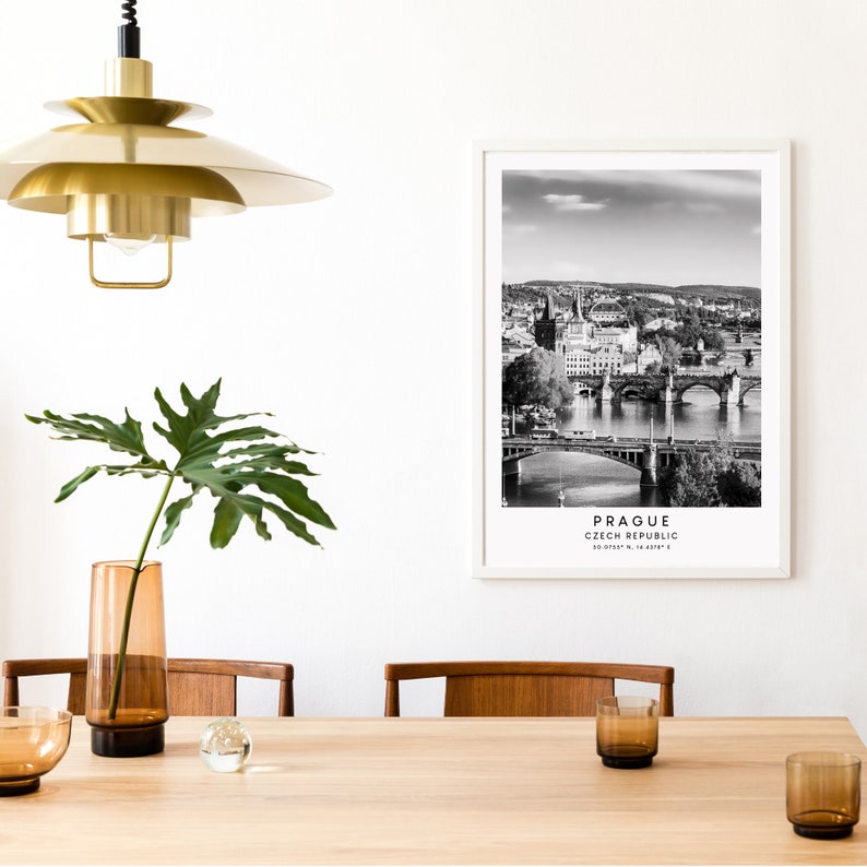 May include: Black and white photograph of Prague, Czech Republic, with the text "Prague, Czech Republic" and coordinates below. The photo shows a cityscape with a river and bridges.