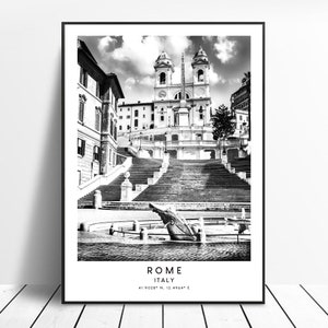 Pode incluir: Uma fotografia a preto e branco da Escadaria Espanhola em Roma, Itália. Os degraus levam a uma igreja com um alto obelisco na frente. Os degraus são cercados por edifícios e árvores. A foto é tirada de um ângulo baixo, olhando para cima para os degraus.