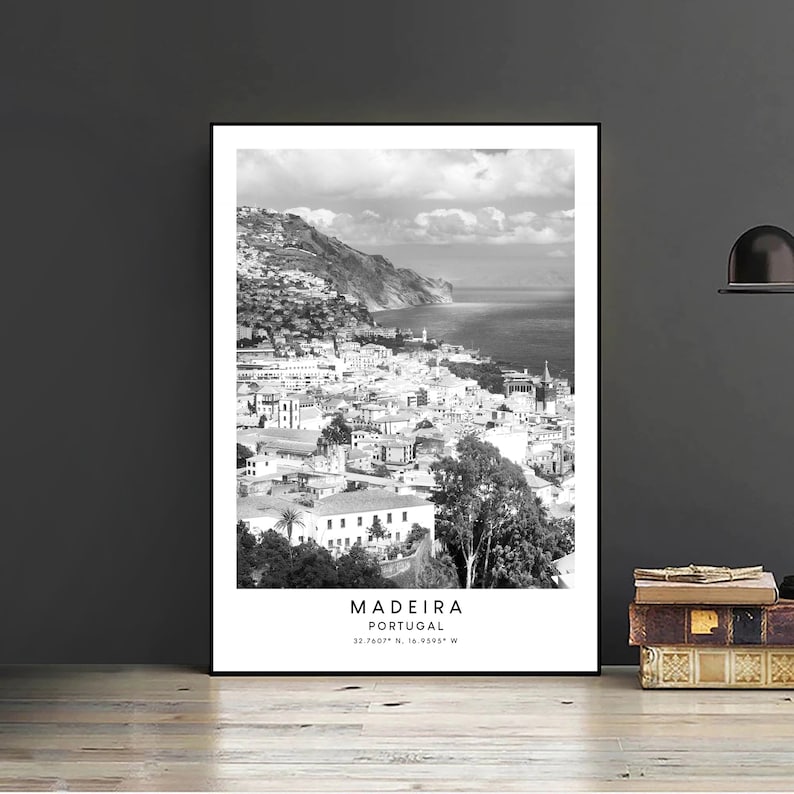 Op de afbeelding: Zwart-witfoto van een kuststad met een berg op de achtergrond. De tekst "MADEIRA PORTUGAL 32.7607&deg; N, 16.9505&deg; W" is onder de afbeelding gedrukt.