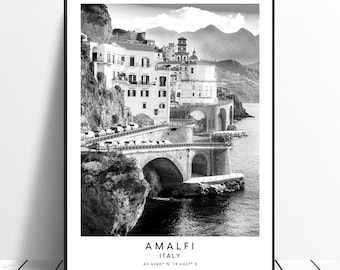 May include: Black and white photograph of a coastal town in Italy. The image shows a series of buildings built into a cliffside, with a bridge leading to the town. The text "Amalfi, Italy 40.6340° N, 14.6027° E" is at the bottom of the image.