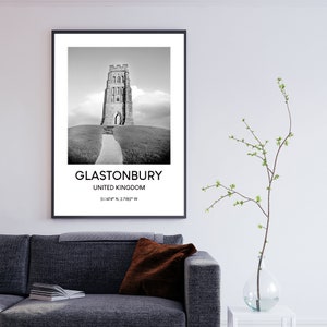 May include: Black and white photograph of Glastonbury Tor, a historic tower in Glastonbury, United Kingdom. The image features a stone tower on a grassy hill with a path leading up to it. The text "Glastonbury, United Kingdom, 51.1424&deg; N, 2.7185&deg; W" is printed below the image.