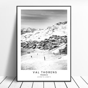 Könnte beinhalten: Schwarzweißfoto einer schneebedeckten Berglandschaft mit einem Dorf, das sich in das Tal schmiegt. Der Text "VAL THORENS FRANKREICH 45.2983° N, 6.5823° E" ist am unteren Rand des Bildes gedruckt.