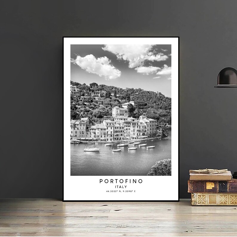 May include: Black and white photograph of the Italian village of Portofino, with colorful buildings on a hillside overlooking a harbor with boats. The text "Portofino, Italy 44.3032&deg; N, 9.2068&deg; E" is at the bottom of the image.