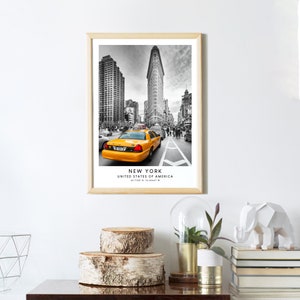 May include: Black and white photograph of a yellow taxi cab driving down a street in New York City. The Flatiron Building is in the background. The text "NEW YORK, UNITED STATES OF AMERICA, 40.7128&deg; N, 74.0060&deg; W" is printed below the image.