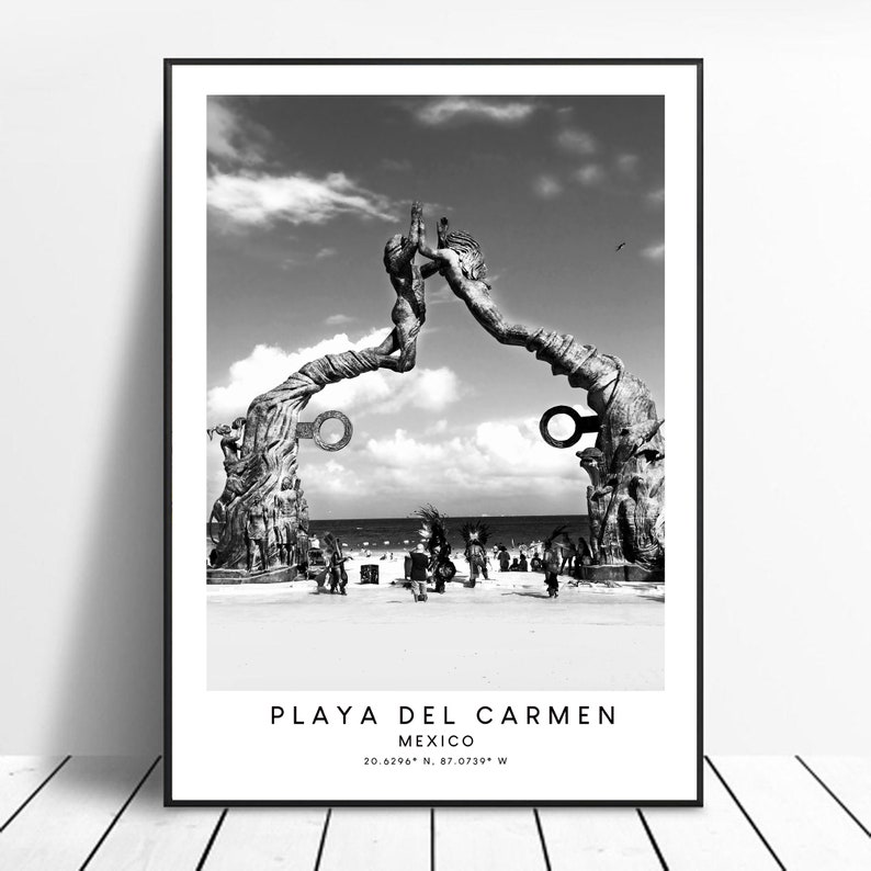 Pode incluir: Fotografia a preto e branco de uma escultura de duas figuras que se alcan&ccedil;am uma &agrave; outra, localizada numa praia de Playa del Carmen, M&eacute;xico. A escultura &eacute; feita de madeira e tem um aspeto r&uacute;stico. A praia &eacute; arenosa e h&aacute; pessoas no fundo.