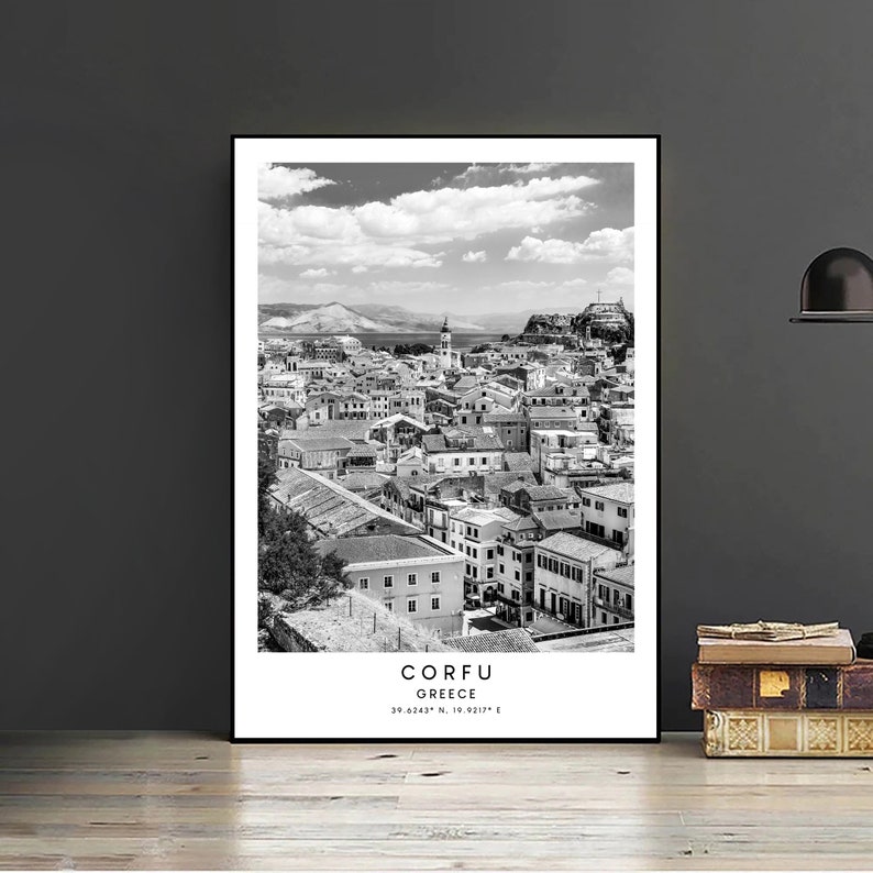 May include: A black and white photograph of the city of Corfu, Greece. The photo shows a cityscape with buildings, a harbour, and a cloudy sky. The text "CORFU GREECE 39.6243&deg; N, 19.9317&deg; E" is printed at the bottom of the photo.