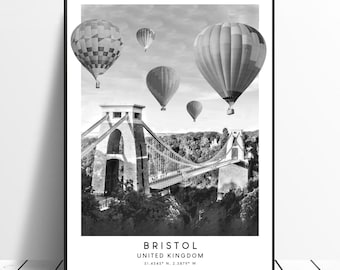 May include: A black and white photograph of the Clifton Suspension Bridge in Bristol, England. The bridge is a suspension bridge that spans the Avon Gorge. There are hot air balloons in the sky above the bridge.