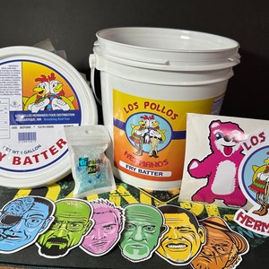 May include: A collection of Breaking Bad-themed merchandise, including Los Pollos Hermanos Fry Batter containers, stickers, and a bag of blue rock candy labeled "Breaking Bad." The items feature cartoon images of characters and the Los Pollos Hermanos logo.