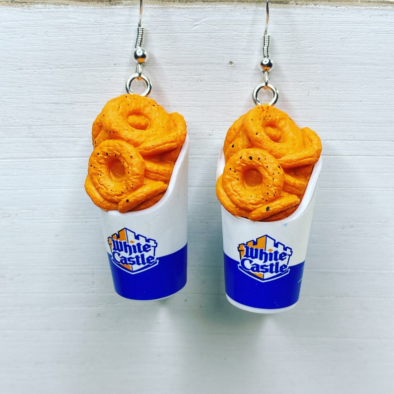 May include: A pair of earrings featuring White Castle onion rings in a small white paper container with blue and yellow accents. The earrings are made of polymer clay and are perfect for any White Castle fan.