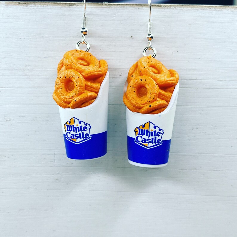 May include: A pair of dangle earrings featuring White Castle-themed charms. Each charm is a small white paper cup with a blue and yellow logo and a depiction of fried onion rings.