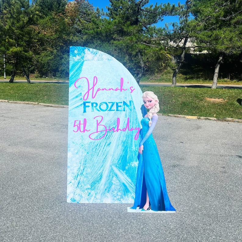 May include: A blue and white Frozen themed birthday party sign with a cutout of Elsa from the movie Frozen. The sign says "Hannah's Frozen 5th Birthday".