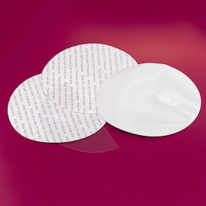 May include: Three white adhesive circles with the text "Stick this side to your skin" repeated around the edge.