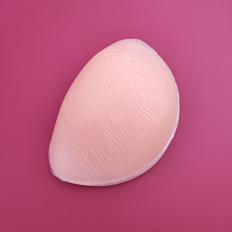 May include: A beige silicone bra insert with a textured surface.