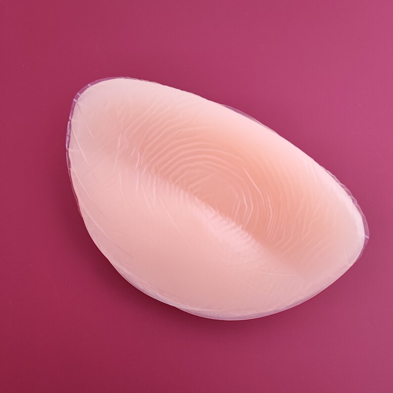 May include: A nude-colored silicone bra insert with a textured surface.