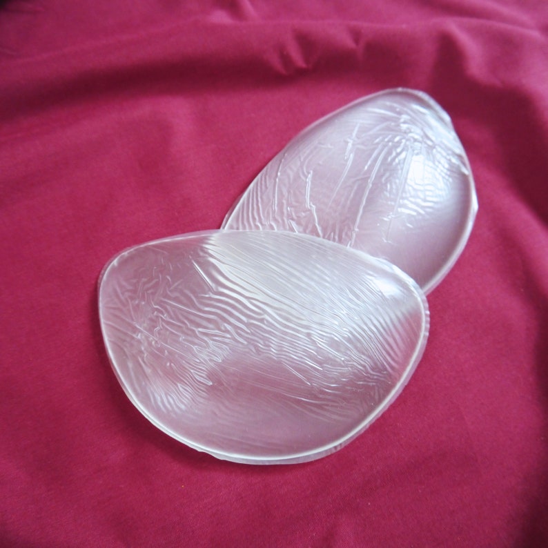 May include: Two clear silicone bra inserts, designed to create a more defined cleavage. The inserts are smooth and have a slightly textured surface.