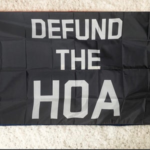 May include: A black flag with the words "DEFUND THE HOA" printed in white.