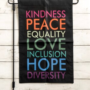 May include: Black garden flag with the words "Kindness", "Peace", "Equality", "Love", "Inclusion", "Hope", and "Diversity" printed in rainbow colors.