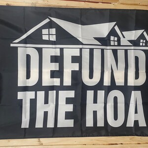 May include: Black flag with white text and a graphic of three houses. The text reads "DEFUND THE HOA".