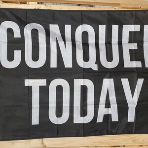 May include: Black flag with white text that reads "CONQUER TODAY".