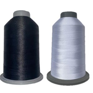 May include: Two spools of thread, one navy blue and one white, are displayed against a white background. Each spool has a gray base and a gray top. The thread is tightly wound around the spool.