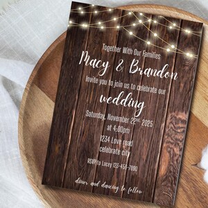 Puede incluir: Una invitación de boda rústica con un fondo de vetas de madera y luces de cadena en la parte superior. La invitación incluye los nombres "Macy & Brandon", detalles de la boda e información de RSVP. El texto está en una fuente blanca y elegante.