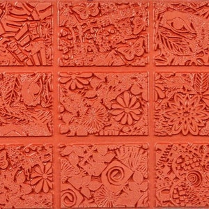 Può includere: Un timbro in gomma rosso con nove quadrati strutturati. Ogni quadrato presenta un design diverso, tra cui fiori, farfalle, foglie e motivi astratti. Il timbro è progettato per l'artigianato e lo scrapbooking.