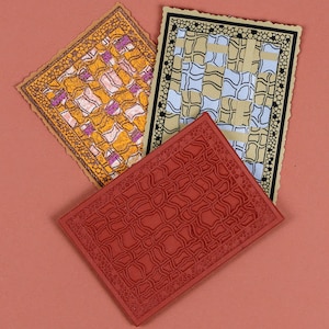 May include: Three different textured rubber stamps with intricate geometric patterns. The stamps are in shades of red, orange, and black.