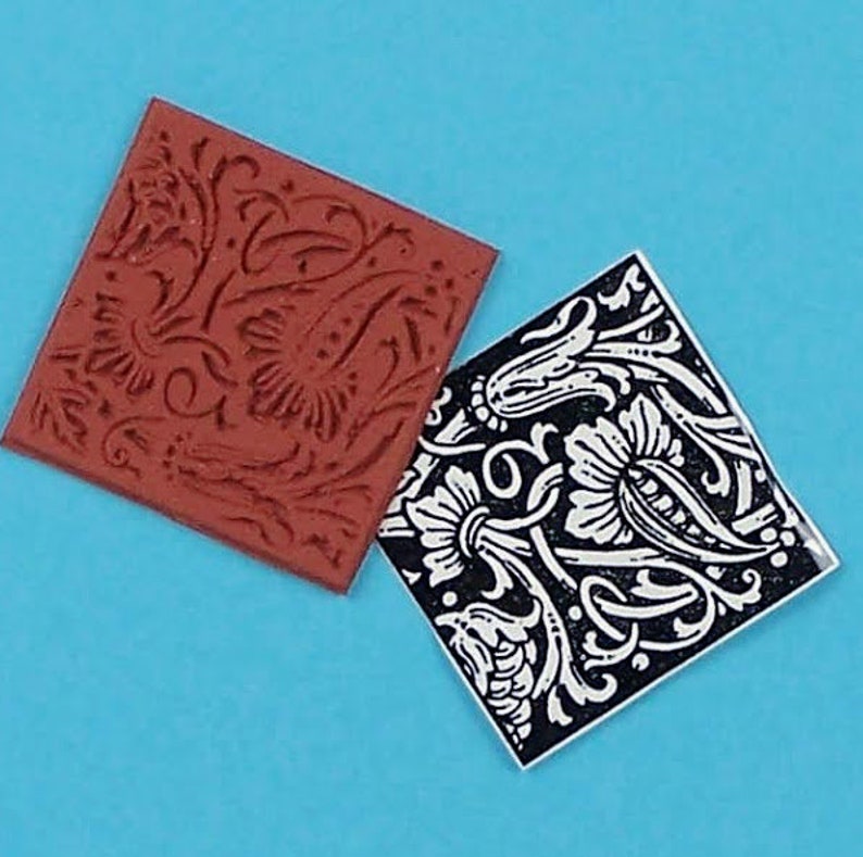 May include: Two square rubber stamps with floral designs. One stamp is a dark reddish-brown color, and the other is black with a white floral pattern. The stamps are set against a bright blue background.
